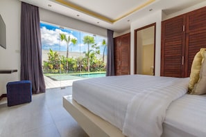 Un dormitorio moderno con una cama grande, vistas a una piscina y armarios de madera.