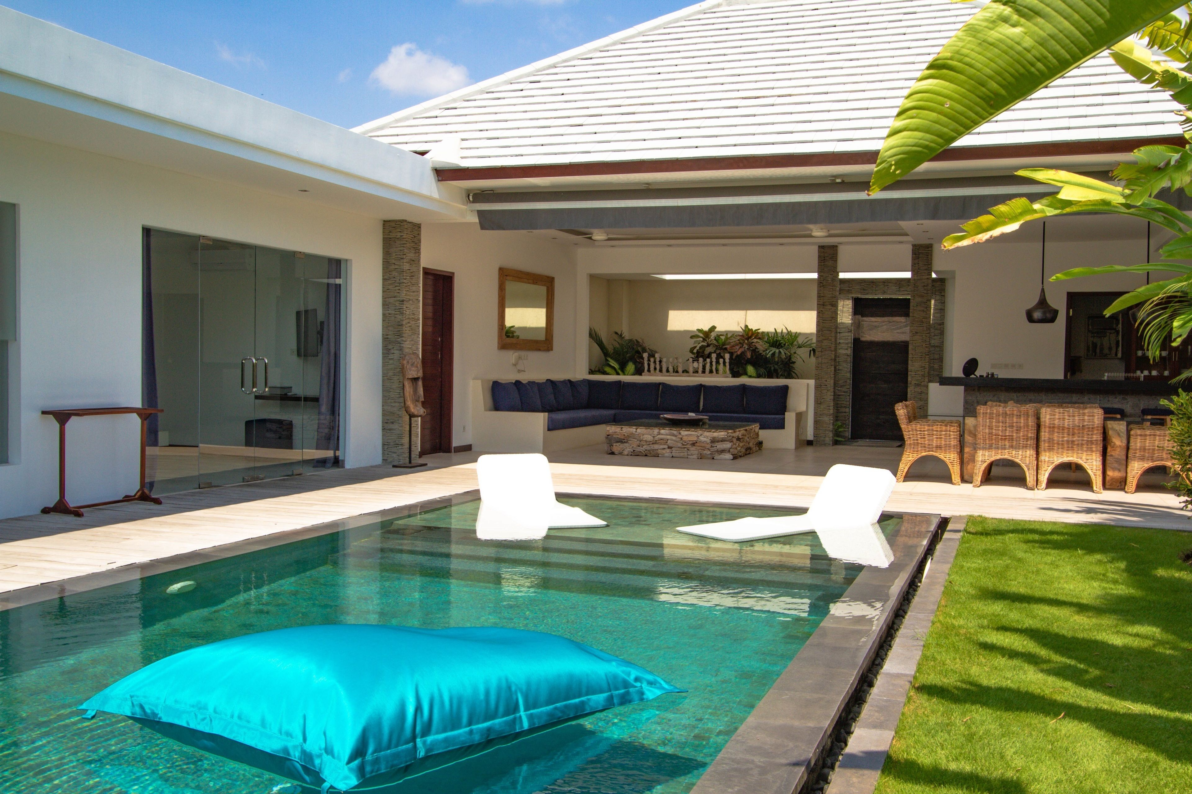 A modern house with a swimming pool, outdoor seating, and a well-maintained lawn.