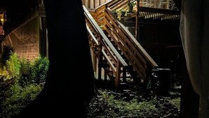 A wooden staircase leading to a building with a lit window, surrounded by greenery and a stone pathway. - Sugar Creek Retreat (Garfield)