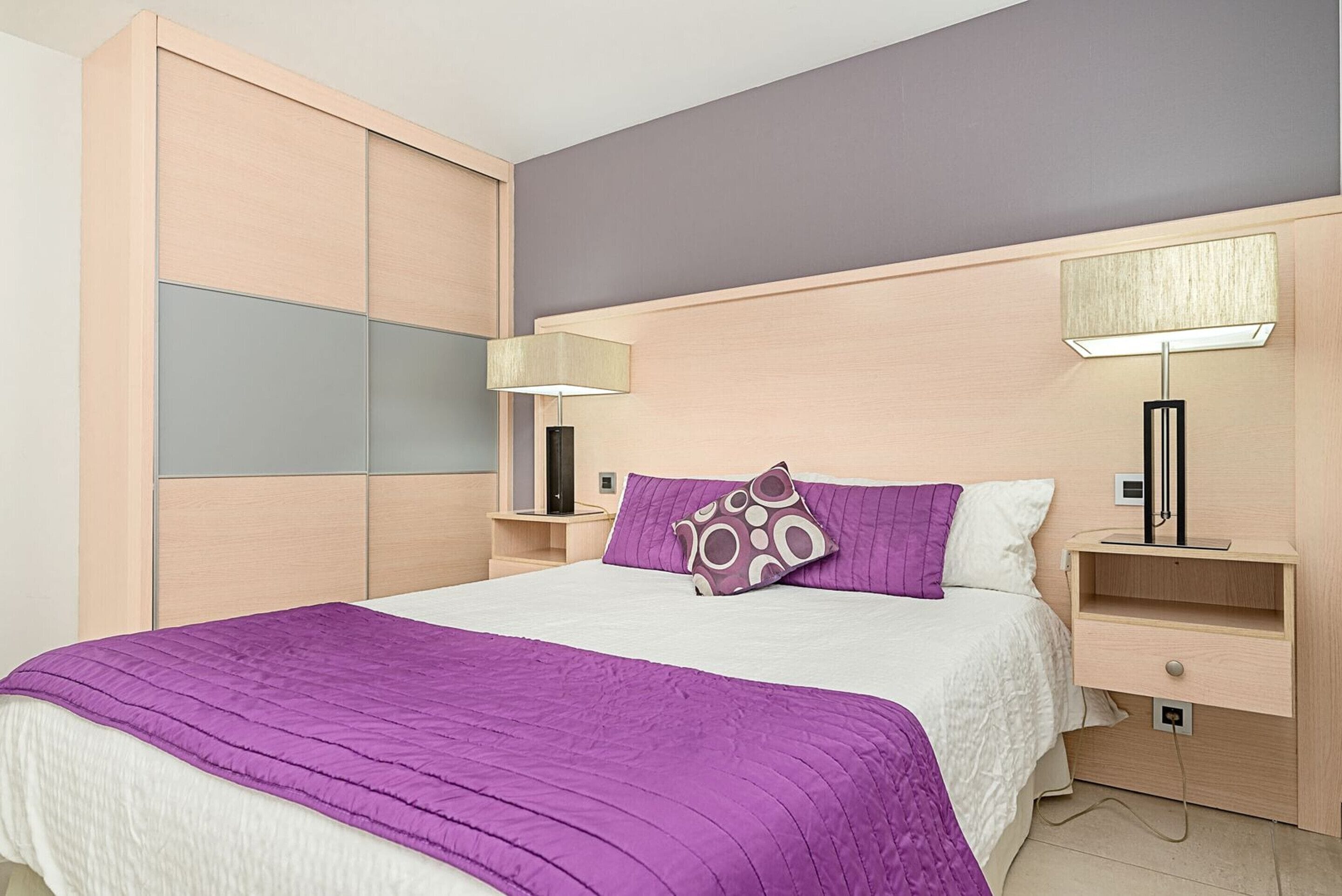A bedroom with a bed, bedside tables, a lamp, and a wardrobe.