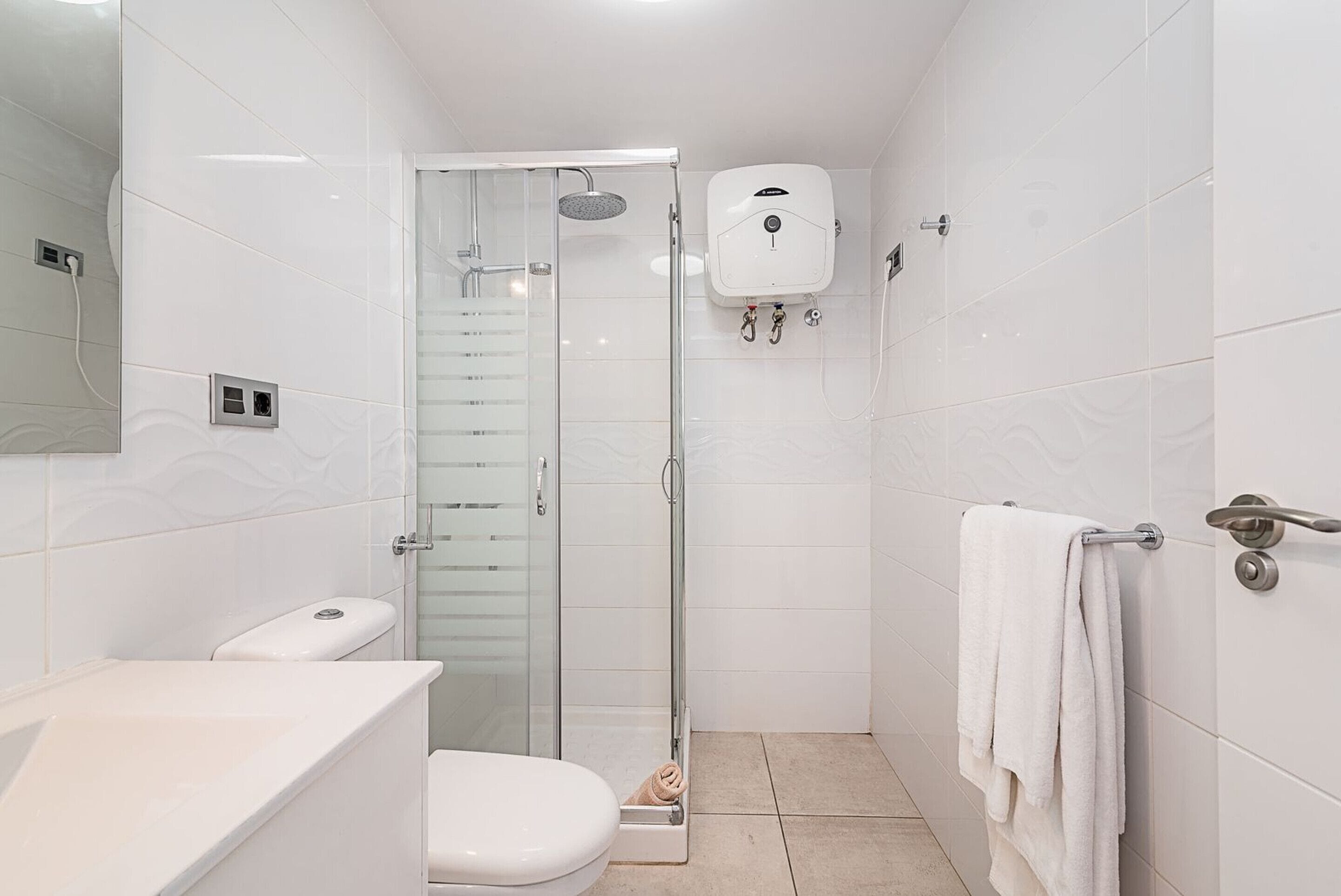 Et badeværelse med toilet, bruser med glasdør og håndklædetørrestativ.