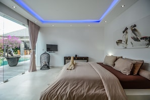 Un dormitorio moderno con una cama grande, un televisor de pantalla plana y un cuadro en la pared.