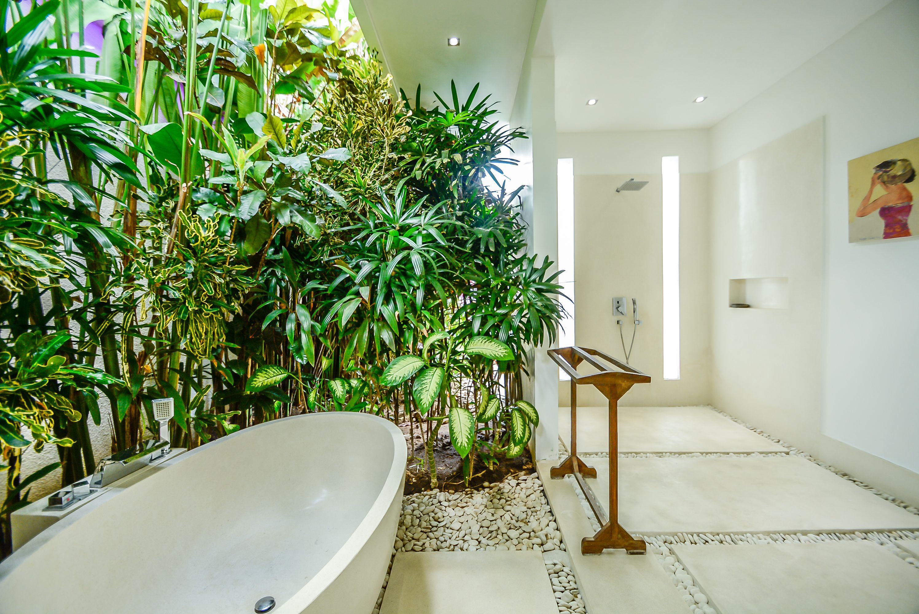 Un baño con una bañera grande, una mesita de madera y una pared cubierta de plantas verdes exuberantes.