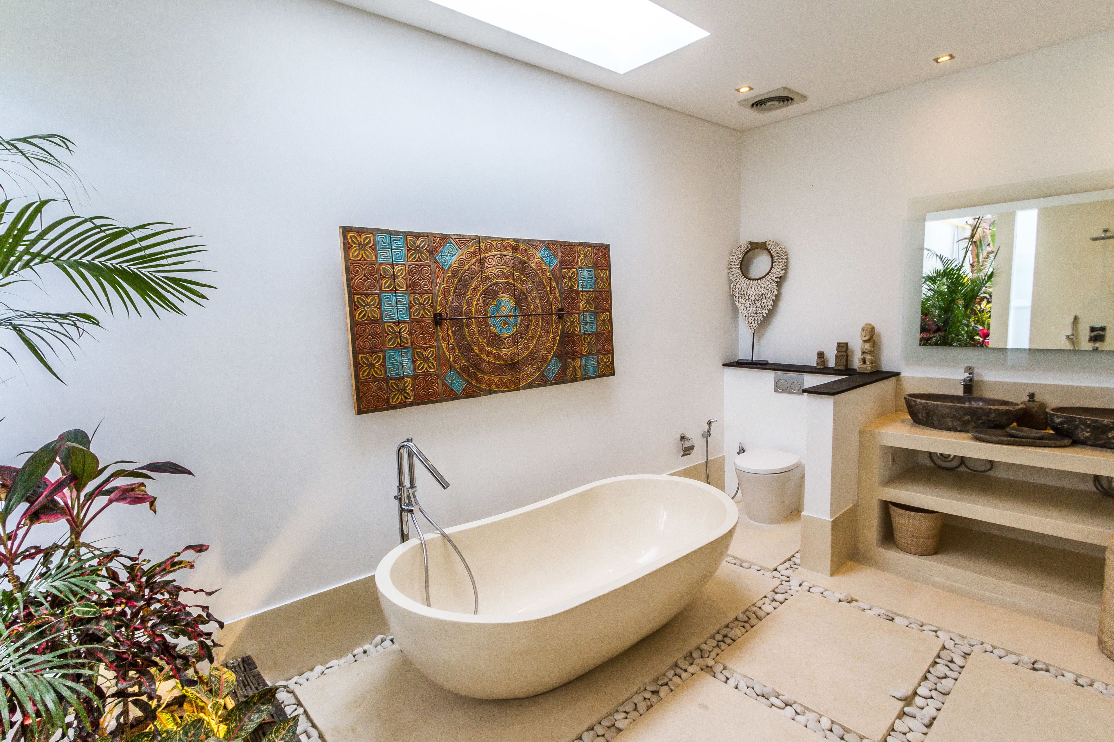 Un baño moderno con una bañera independiente, un espejo grande y un adorno en la pared.