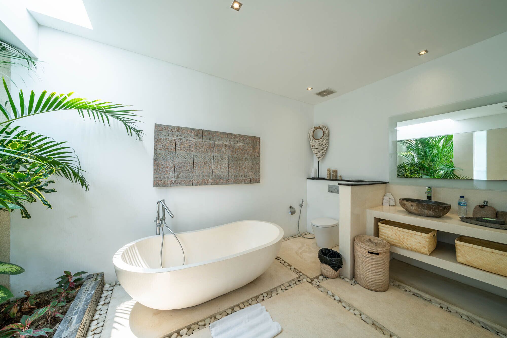 A modern bathroom with a freestanding bathtub, a large mirror, and a wall-mounted sink.