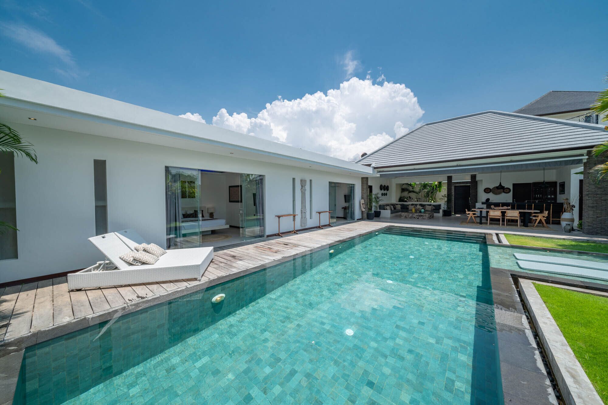 Une maison moderne dotée d’une piscine, d’un patio et d’un espace extérieur aménagé et abrité.