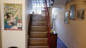 A staircase with wooden steps and a red handrail, leading to a landing with framed pictures on the wall. - Affittacamere Grandpa Mau (Lucca)