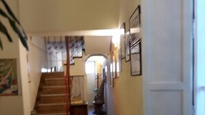 A dining area with a table and chairs, a staircase, and a hallway leading to another room. - Affittacamere Grandpa Mau (Lucca)