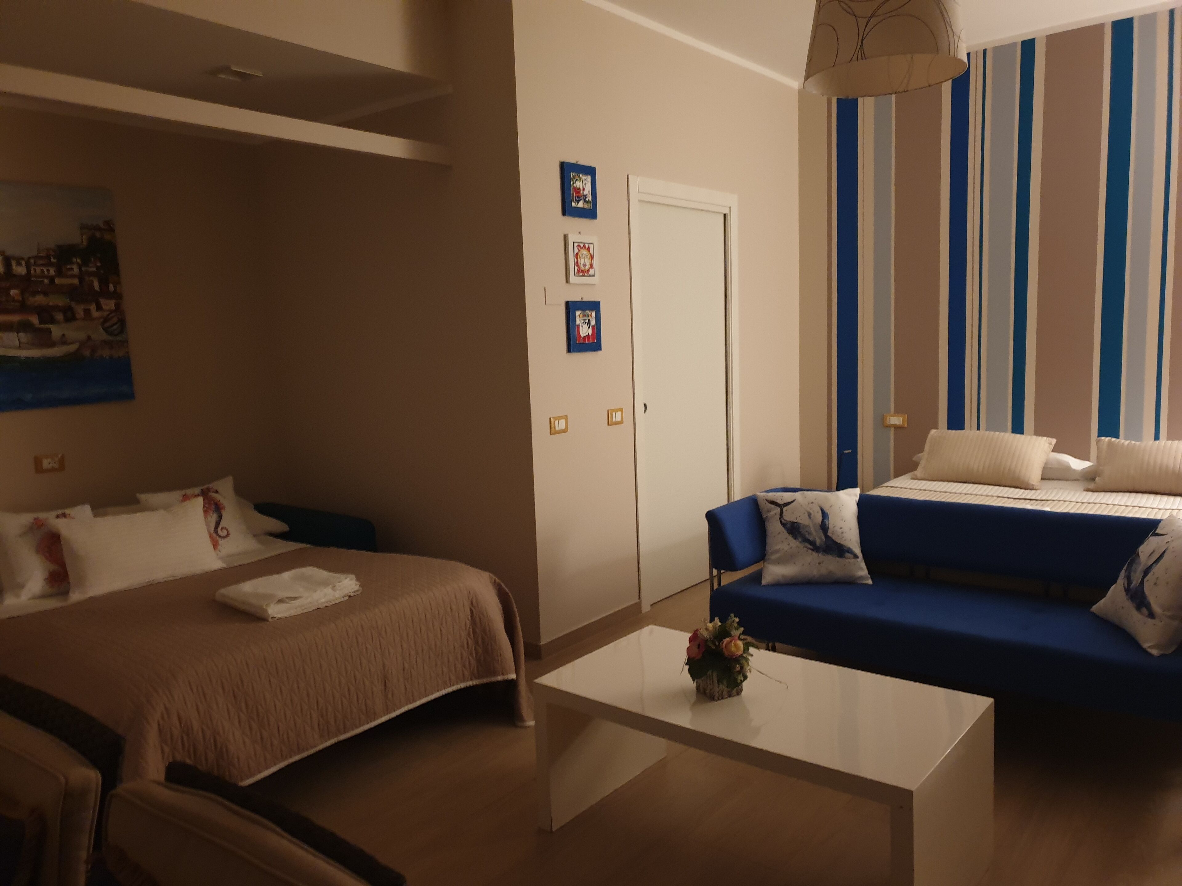 A hotel room with a bed, a sofa, a coffee table, and a door.