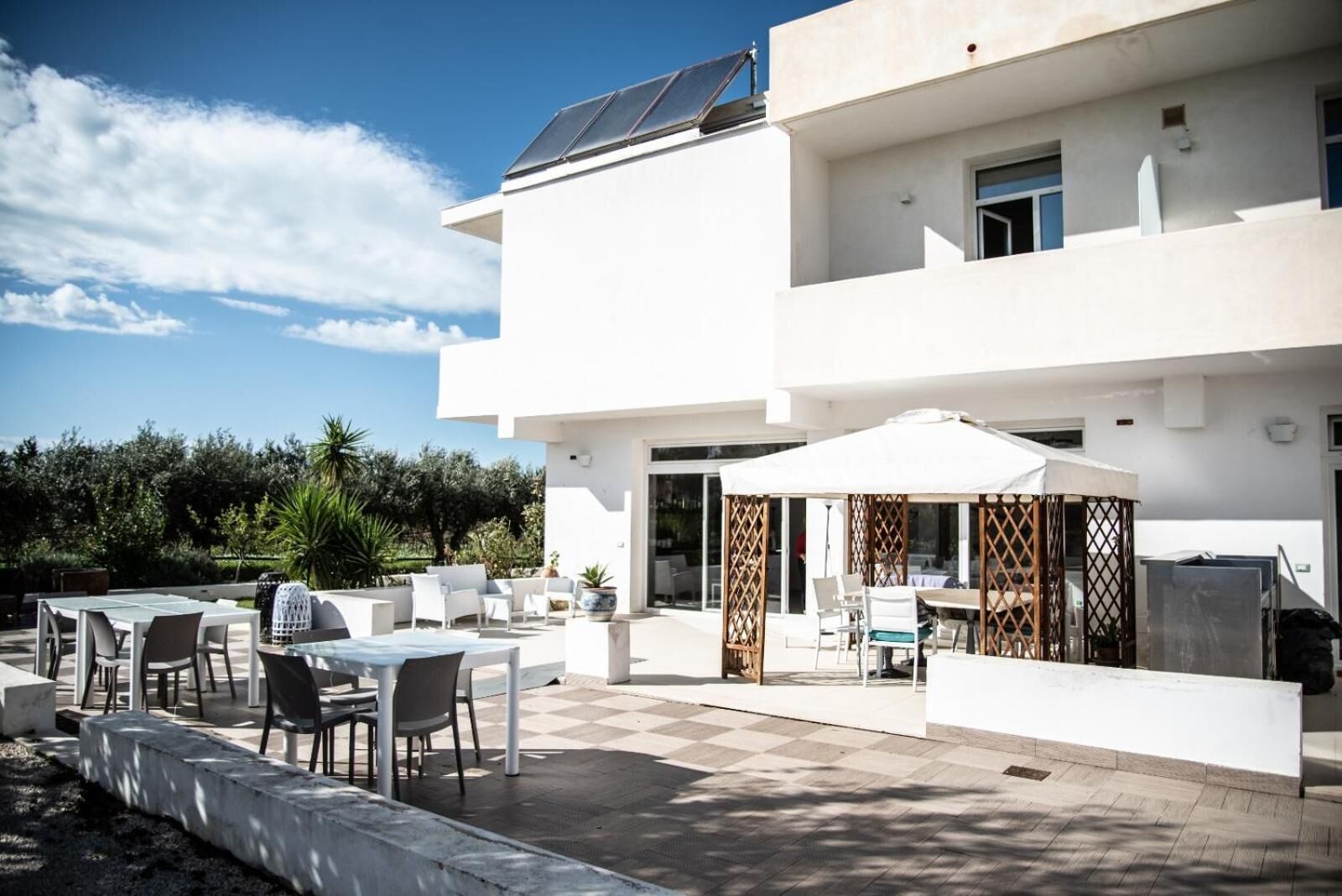 A modern two-story building with a patio area featuring outdoor seating and a covered dining area.