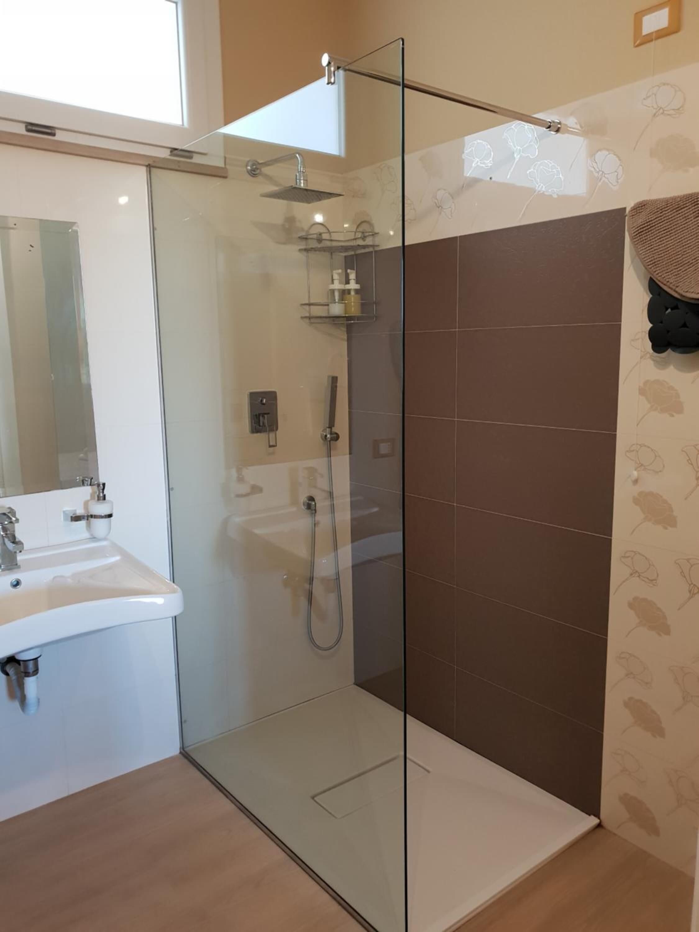 A modern bathroom with a glass-enclosed shower, a white sink, and a mirror.