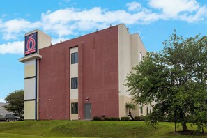 A modern building with a prominent '6' sign, likely a motel or hotel, with a flat roof and a large entrance door.