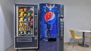 Máquina automática com logotipo Pepsi, contendo diversos snacks e bebidas.