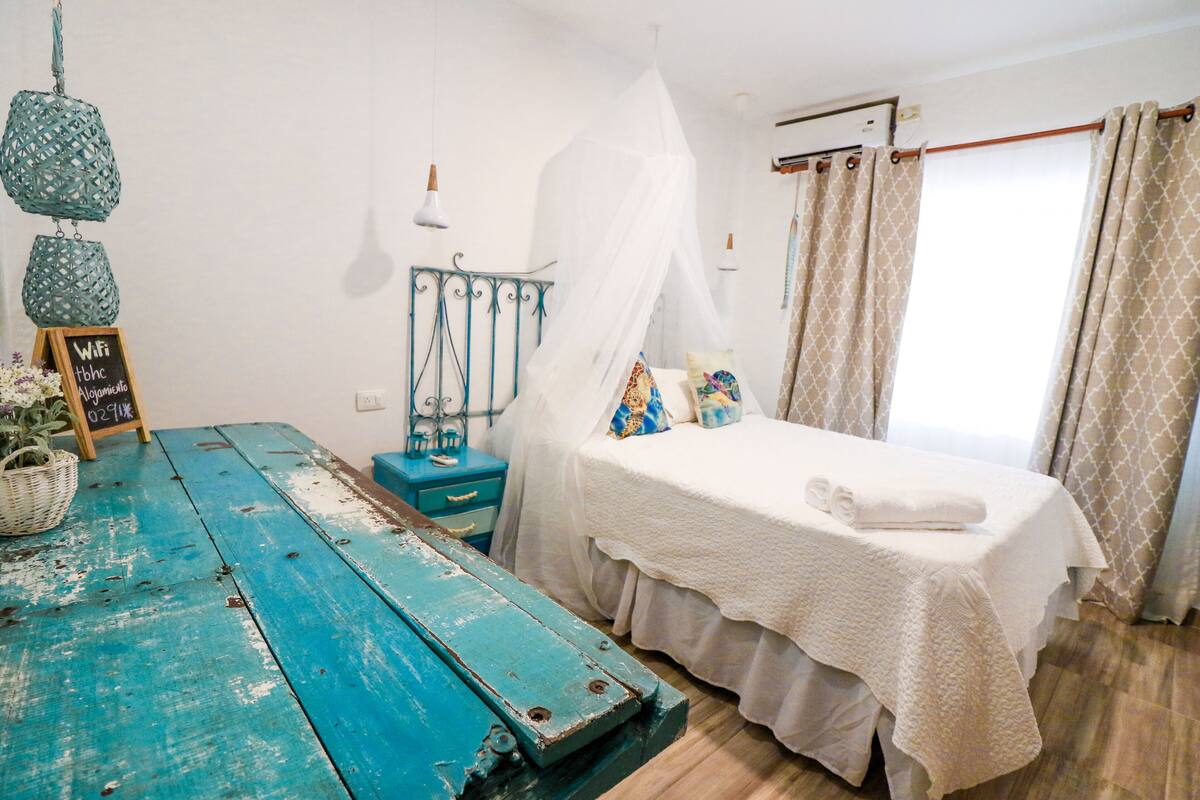 Une chambre comprenant un lit, une table en bois, un panier et un panneau indiquant la présence d’une connexion Wi-Fi.