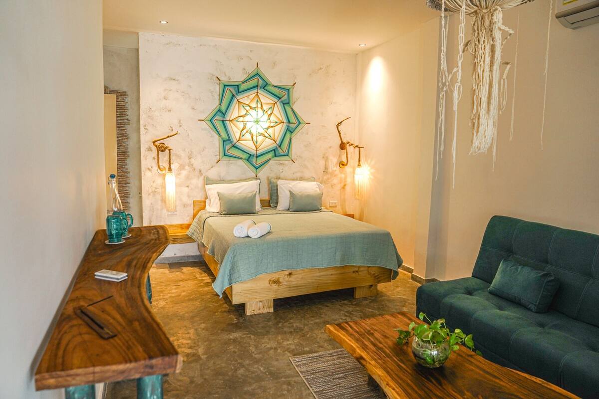 Une chambre confortable avec un lit en bois, un canapé vert et un élément décoratif mural.