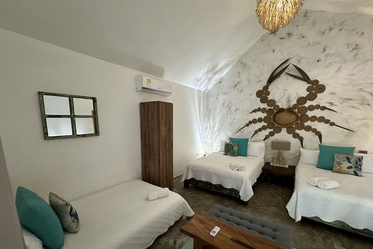 Une chambre avec deux lits, une armoire en bois, un miroir et un élément décoratif mural.
