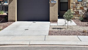 Una casa moderna de dos pisos con garaje, un balcón y fachada de piedra.