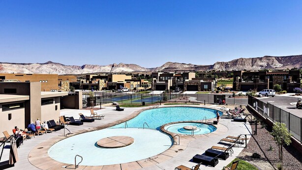 A resort with a large pool, lounge chairs, and a mountainous backdrop. - Greenwind (St. George)