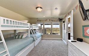 A bedroom with bunk beds, a fan, a dresser, and a window with a view. - Greenwind (St. George)