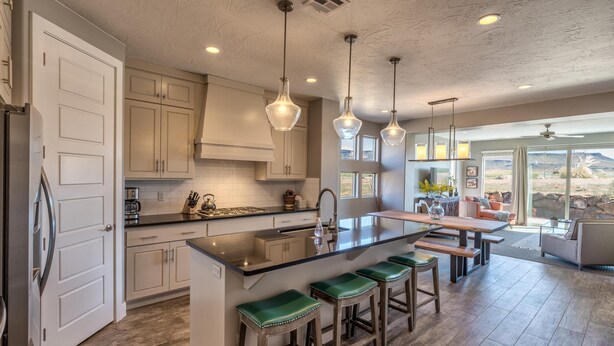 A modern kitchen with a central island, bar stools, and pendant lighting. - Snow Canyon Sunrise (St. George)