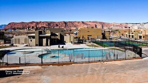 Un moderno complejo arquitectónico con piscina, rodeado de montañas desérticas.