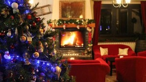 Ein gemütliches Wohnzimmer mit Kamin, roten Sofas und einem geschmückten Weihnachtsbaum.