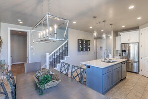 A modern kitchen with a central island, stainless steel appliances, and a staircase leading to another level.