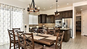A spacious kitchen with dark wooden cabinets, stainless steel appliances, and a central island. - Stay On Course (St. George)