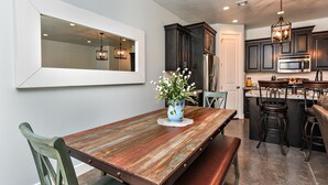 A dining area with a wooden table, chairs, and a vase of flowers. - Desert Cool (St. George)