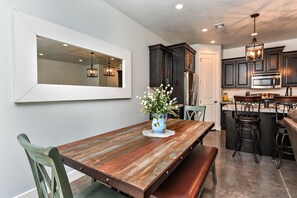 A dining area with a wooden table, chairs, and a vase of flowers.