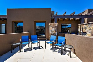 A patio with outdoor seating, a stone wall, and a pergola.