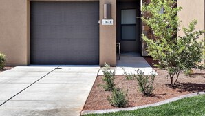 A modern two-story building with a garage, a balcony with blue chairs, and a stone facade. - Desert Cool (St. George)