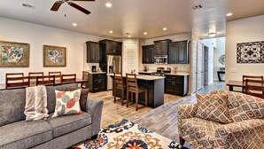 A modern kitchen with dark cabinets, a central island, and a ceiling fan. - The Great Escape (St. George)