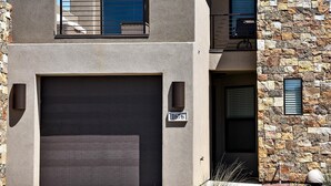 A modern two-story house with a garage, stone facade, and a balcony. - The Great Escape (St. George)