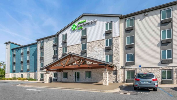 Een Stay Ameriga hotel met een gevel van steen, meerdere ramen en een overdekte entree.
