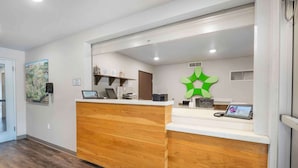 Een receptiegedeelte met een houten receptiebalie, een groen decoratief element en een kaart aan de muur.