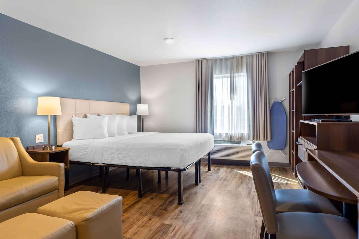 A hotel room with a bed, a sofa, a TV, and a desk.