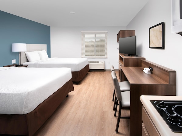 A hotel room with two beds, a desk with a chair, a television, and a small table with a phone.