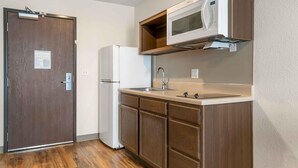 Una cocina compacta equipada con refrigerador, microondas y pileta.