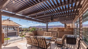 An outdoor patio with a pergola, seating area, and a view of mountains. - 18th Fairway to Heaven (St. George)
