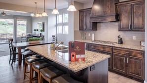 A modern kitchen with dark wood cabinets, a granite countertop, and a central island with bar stools. - 18th Fairway to Heaven (St. George)