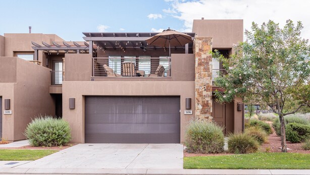 A modern two-story building with a garage, outdoor seating area, and a small patio with an umbrella. - 18th Fairway to Heaven (St. George)