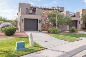 A modern residential building with a garage, stone facade, and well-maintained landscaping.