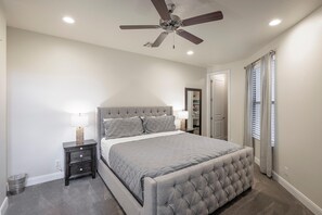 A bedroom with a bed, nightstands, a ceiling fan, and a walk-in closet.