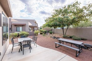An outdoor patio with a table and chairs, surrounded by a landscaped garden and a building with a modern design.