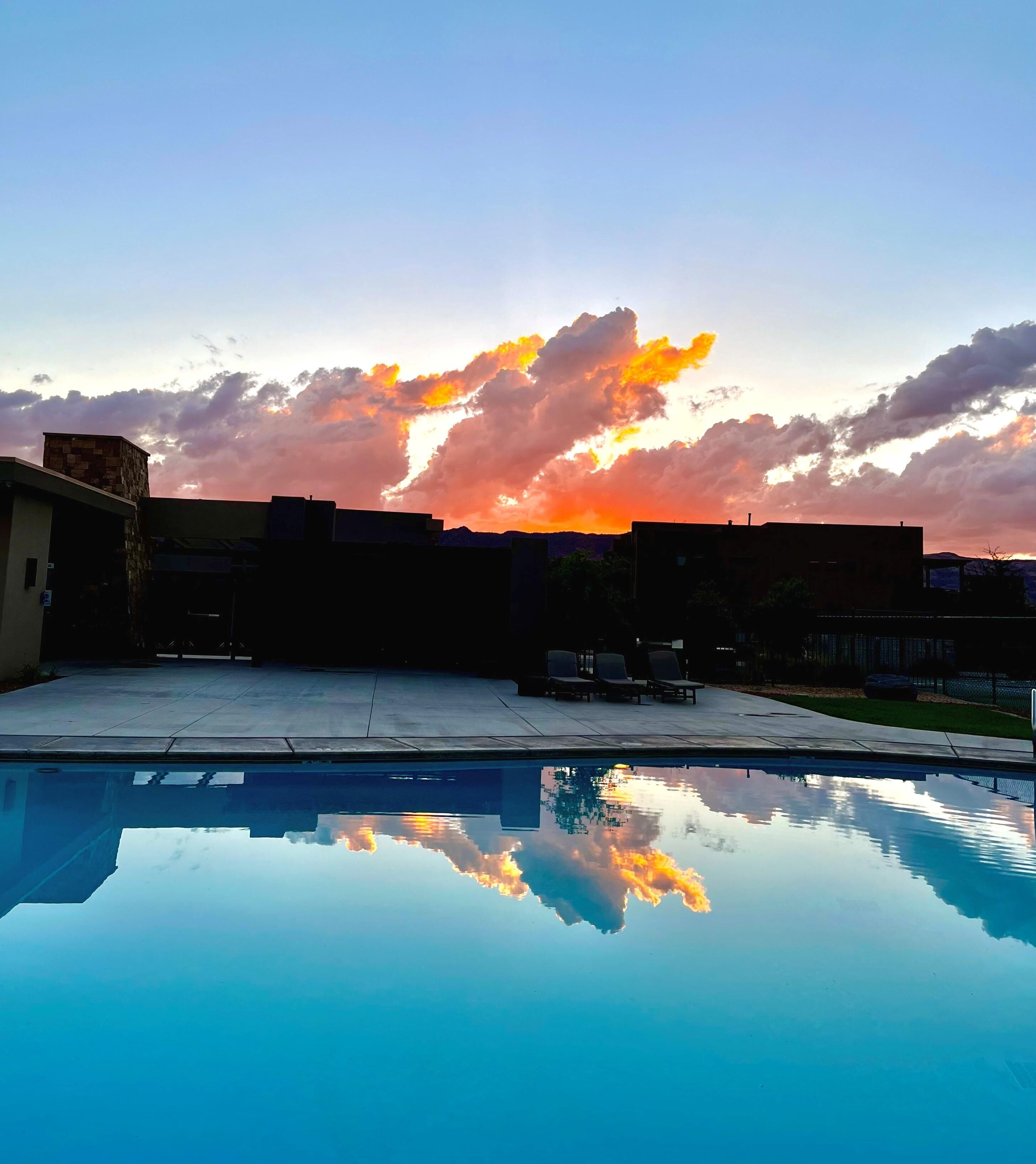 A swimming pool reflecting a sunset sky with clouds.