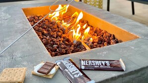 Een vuurkuil met marshmallows en chocoladerepen, omringd door zitplaatsen.