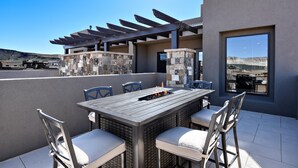 An outdoor patio with a table and chairs, a pergola, and a stone wall. - High Desert Hideaway (St. George)