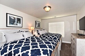 A bedroom with a large bed, a dresser, a lamp, and two framed pictures on the wall. - High Desert Hideaway (St. George)