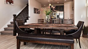 A dining area with a large wooden table, black leather chairs, and a bench. - The Painted Horse (St. George)